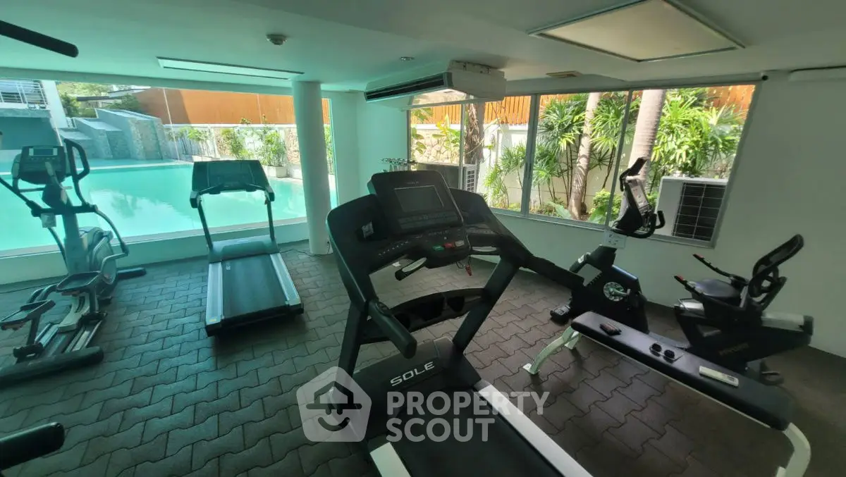Modern gym with pool view and state-of-the-art equipment in luxury residential complex.