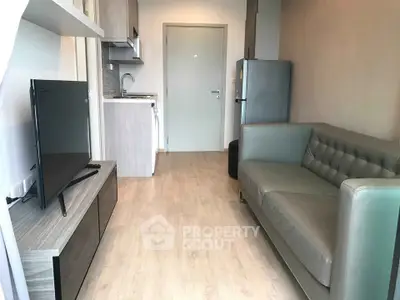 Modern living room with sleek furniture and compact kitchen in open layout apartment.