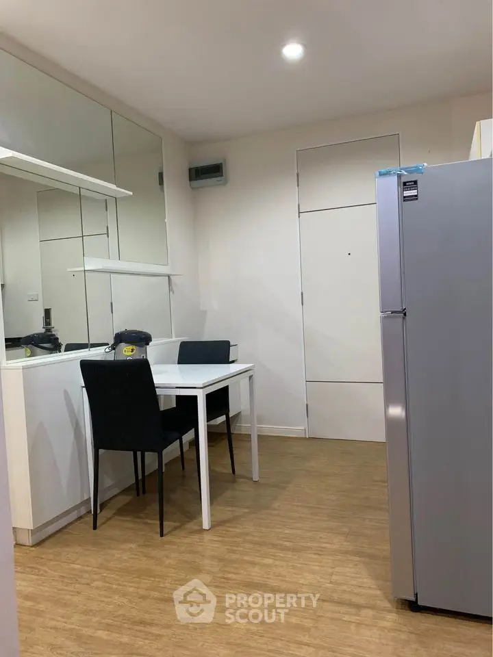 Modern kitchen with sleek fridge and dining area in stylish apartment.