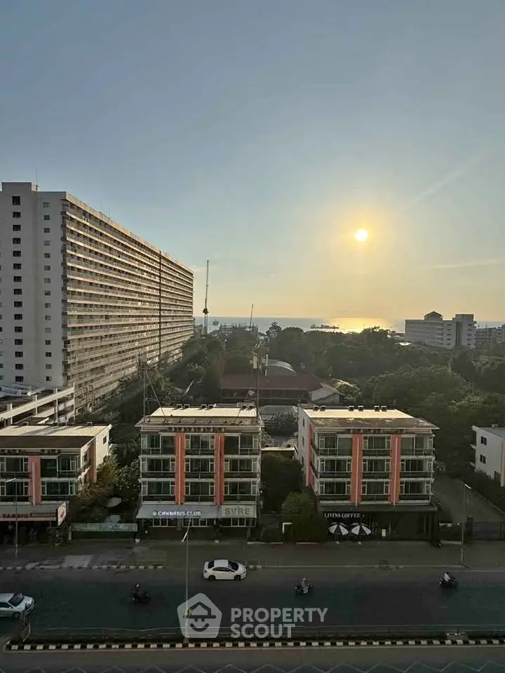Stunning sunset view from high-rise building overlooking cityscape and distant ocean horizon.