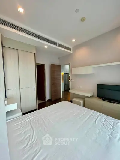 Modern bedroom with sleek furniture and built-in wardrobe in a stylish apartment.