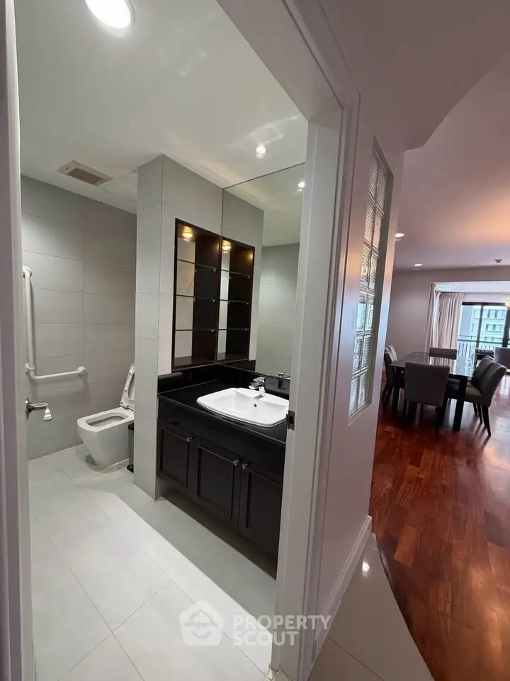 Spacious apartment with modern bathroom and elegant dining area, featuring sleek fixtures and hardwood floors.