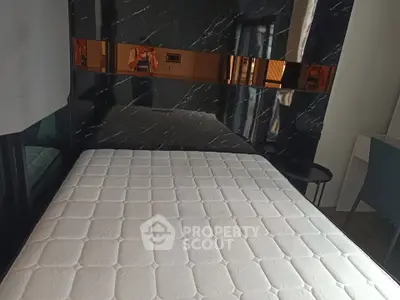 Modern bedroom with stylish black marble accent wall and comfortable mattress.