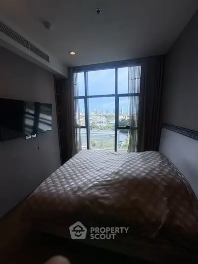 Cozy bedroom with large window offering stunning city view, modern decor, and wall-mounted TV.