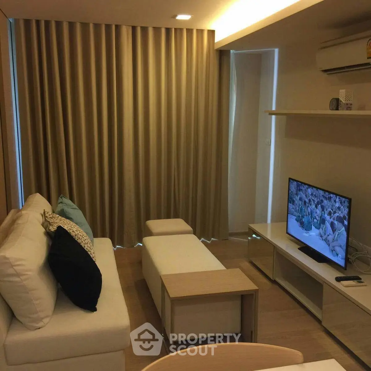 Cozy living room with modern decor, featuring a comfortable sofa, flat-screen TV, and elegant curtains.