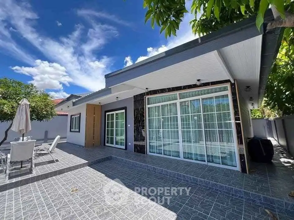 Modern single-story home with spacious patio and large glass doors under a clear blue sky.