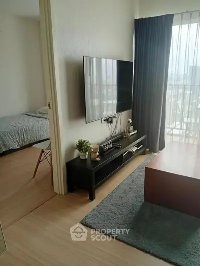 Modern living room with sleek TV setup and cozy decor, adjacent to a bright bedroom.