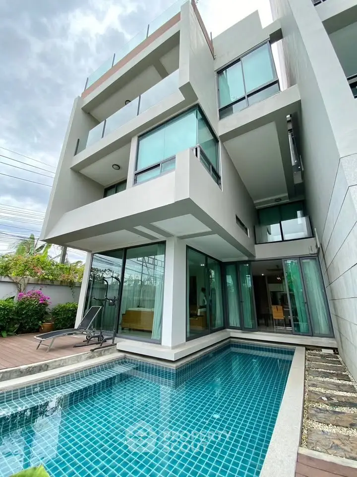 Modern luxury villa with private pool and large glass windows, showcasing contemporary architecture.