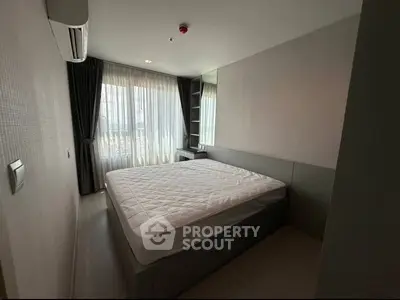 Modern bedroom with large window and stylish decor in a contemporary apartment.