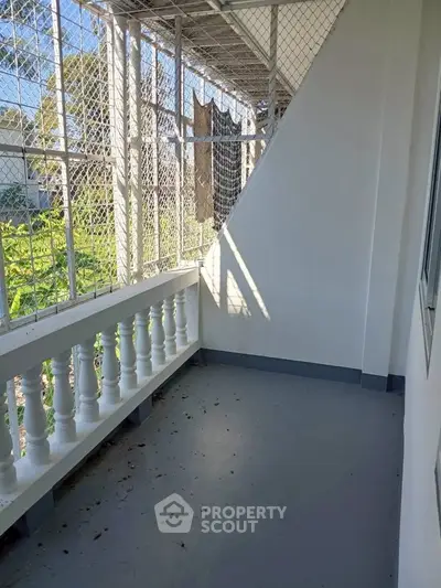 Spacious balcony with safety netting and garden view, perfect for relaxation and outdoor enjoyment.
