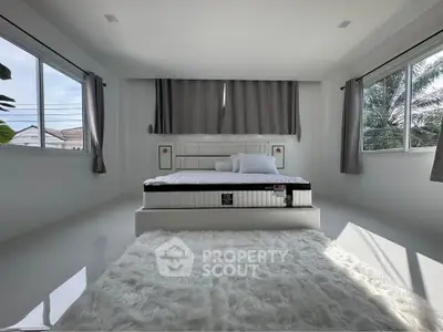 Spacious bedroom with large windows and modern decor, featuring a plush white rug and elegant bed.