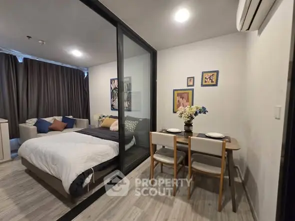 Modern studio apartment with cozy bedroom and dining area, featuring stylish decor and ample natural light.