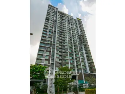 Modern high-rise building with lush greenery and clear sky view, perfect for urban living.
