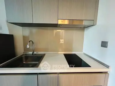 Modern kitchen with sleek cabinetry and electric cooktop in a stylish apartment.