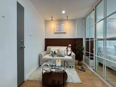 Cozy living room with modern decor and glass partition to bedroom