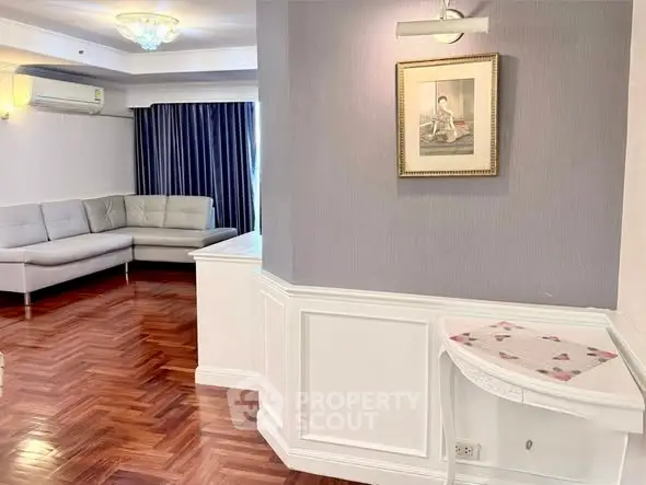 Elegant living room with parquet flooring and modern corner sofa, featuring stylish wall art and ambient lighting.