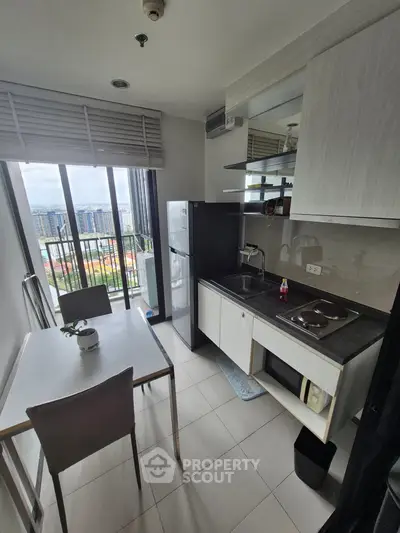Modern kitchen with city view, featuring sleek cabinetry and dining area in a high-rise apartment.