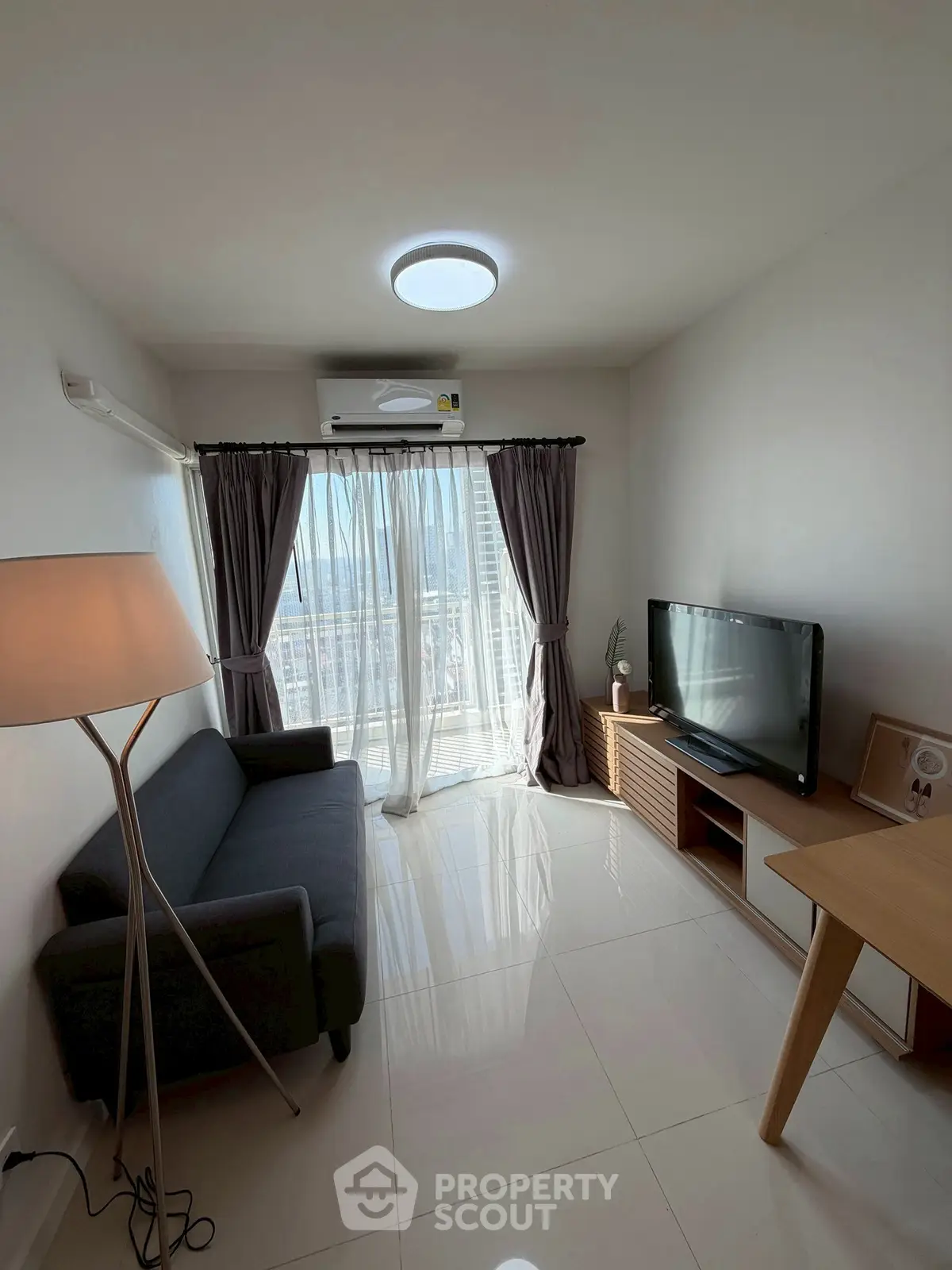 Modern living room with sleek furniture and large window offering city view