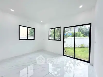 Bright and spacious room with large windows and garden view, perfect for modern living.