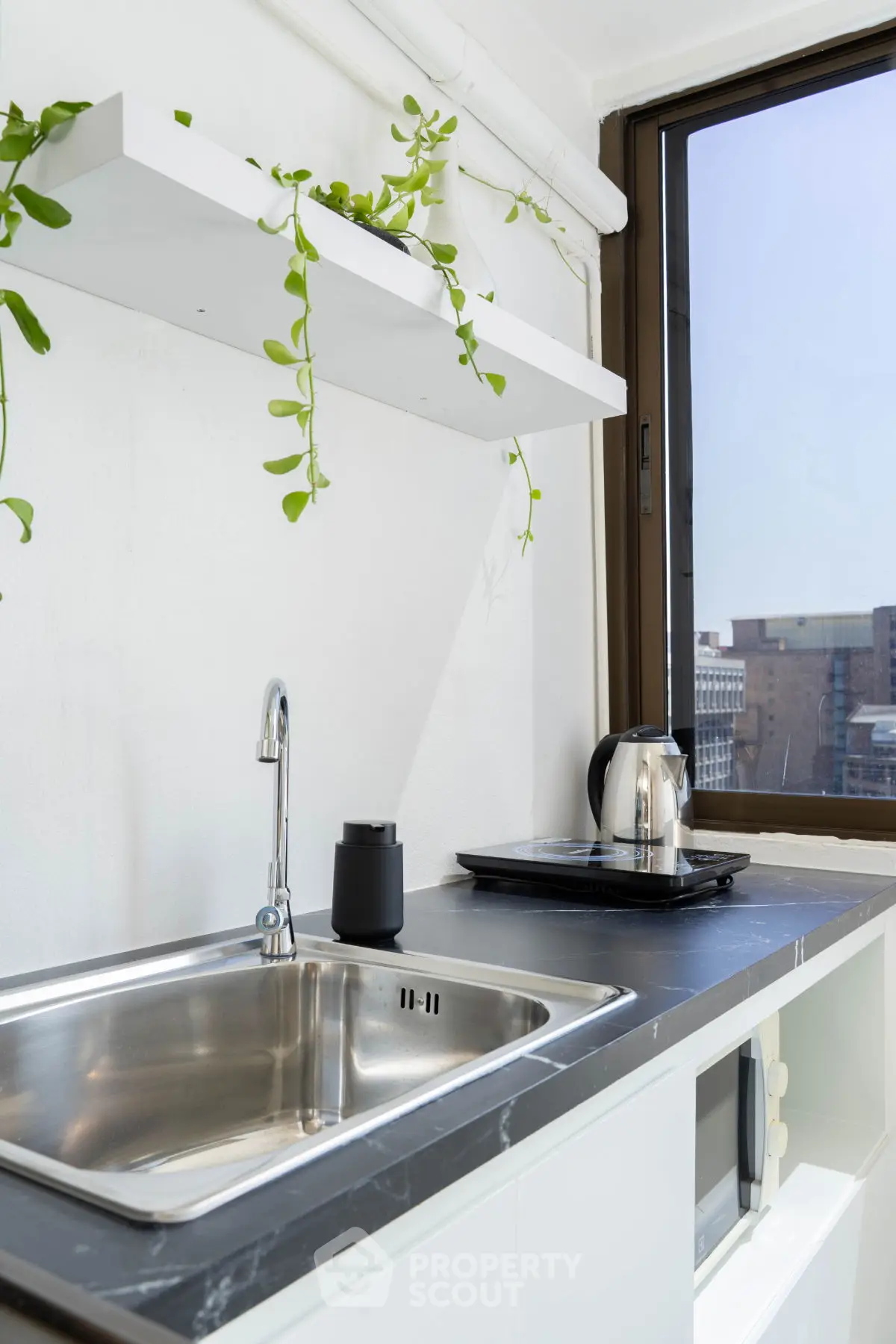 Modern kitchen with sleek sink and city view, featuring a stylish countertop and greenery.