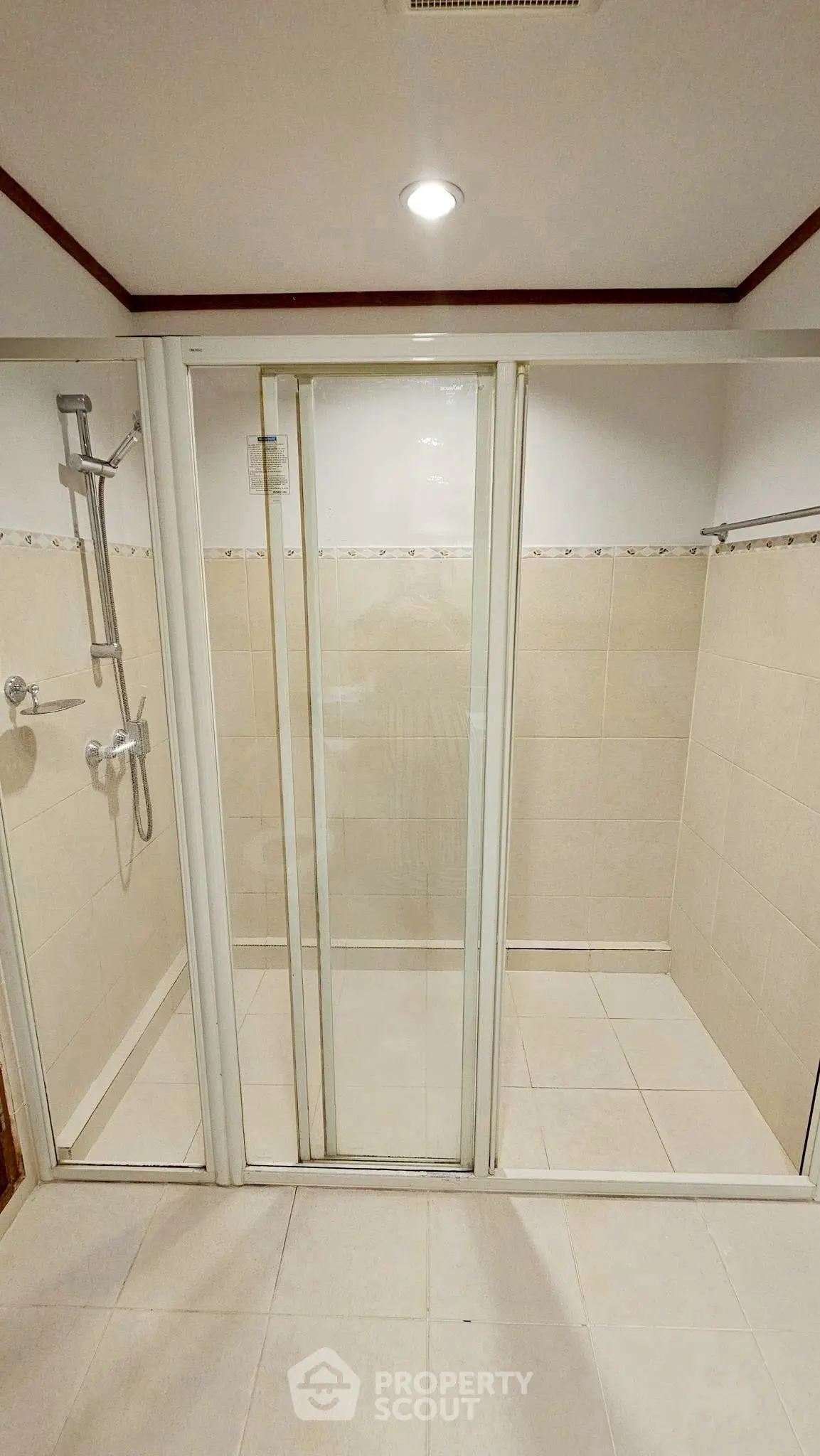 Spacious bathroom with modern shower enclosure and tiled walls.