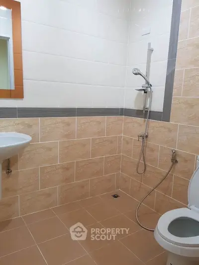 Modern bathroom with tiled walls, shower, and toilet in a real estate property.