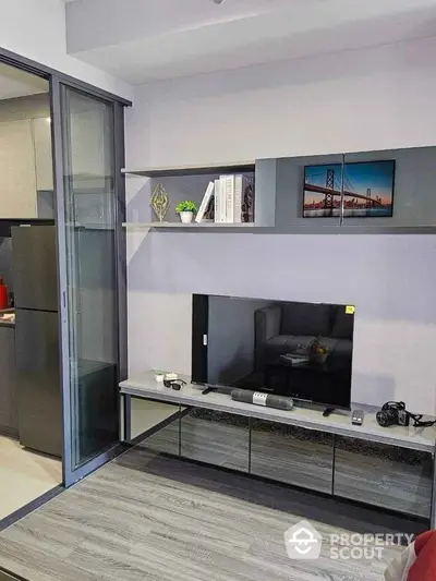 Modern living room with sleek TV unit and sliding glass door to kitchen.