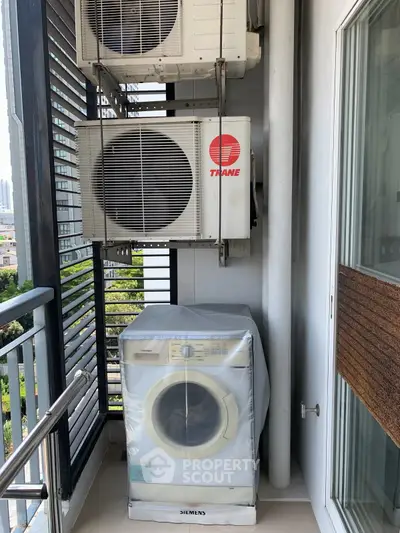 Modern balcony with washing machine and air conditioning units in urban setting.