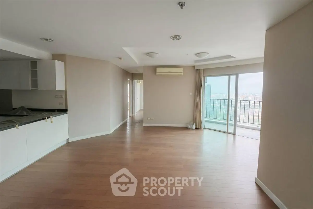 Spacious open-plan living room with balcony and city view in modern apartment.