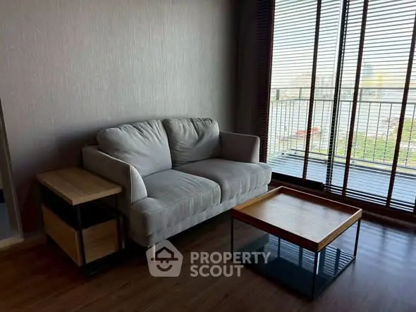 Cozy living room with modern sofa and coffee table, featuring large windows and balcony view.