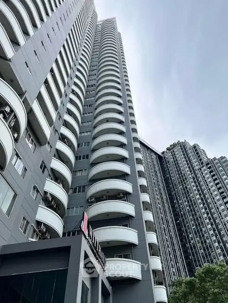 Stunning high-rise building with modern architecture and curved balconies in urban setting.