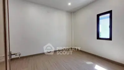 Spacious empty room with wooden flooring and a single window, perfect for customization.