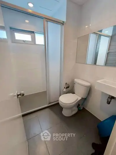 Modern bathroom with sleek design, featuring a glass shower, toilet, and sink in a compact layout.
