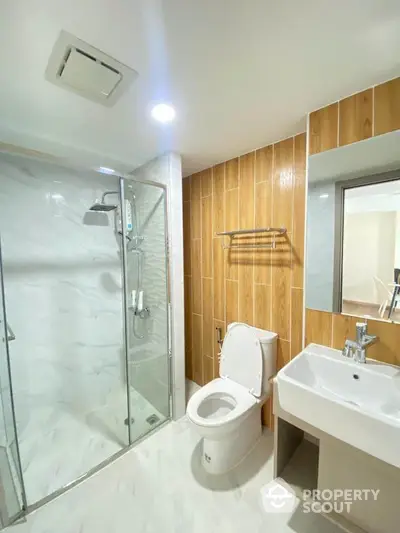 Modern bathroom with glass shower and wooden accents in luxury apartment