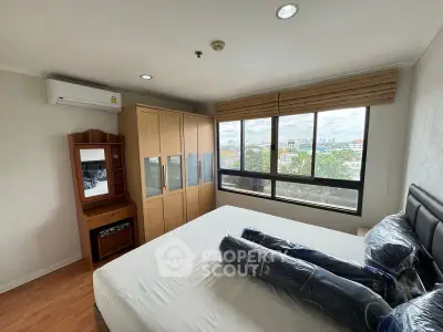 Spacious bedroom with large window offering stunning city views, featuring modern furniture and ample storage.