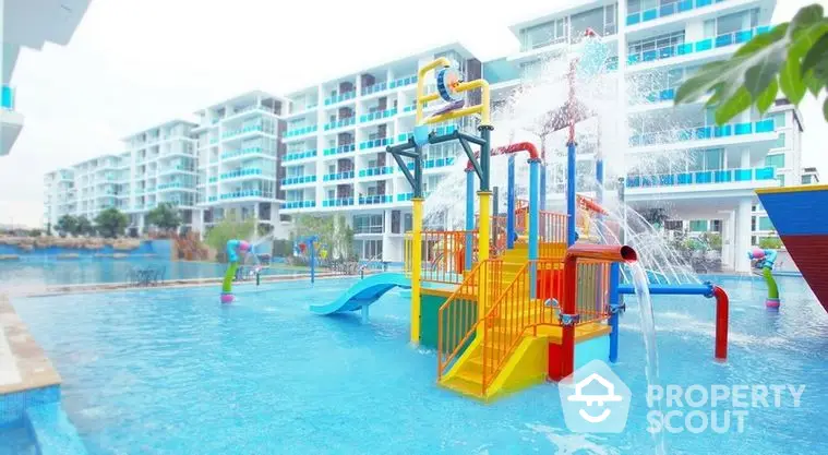 Vibrant family-friendly pool with water slides and play structures at a modern residential complex, showcasing a fun and active community lifestyle.