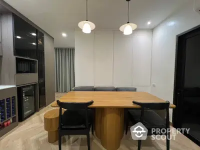 Modern dining area with wooden table and stylish lighting in contemporary home