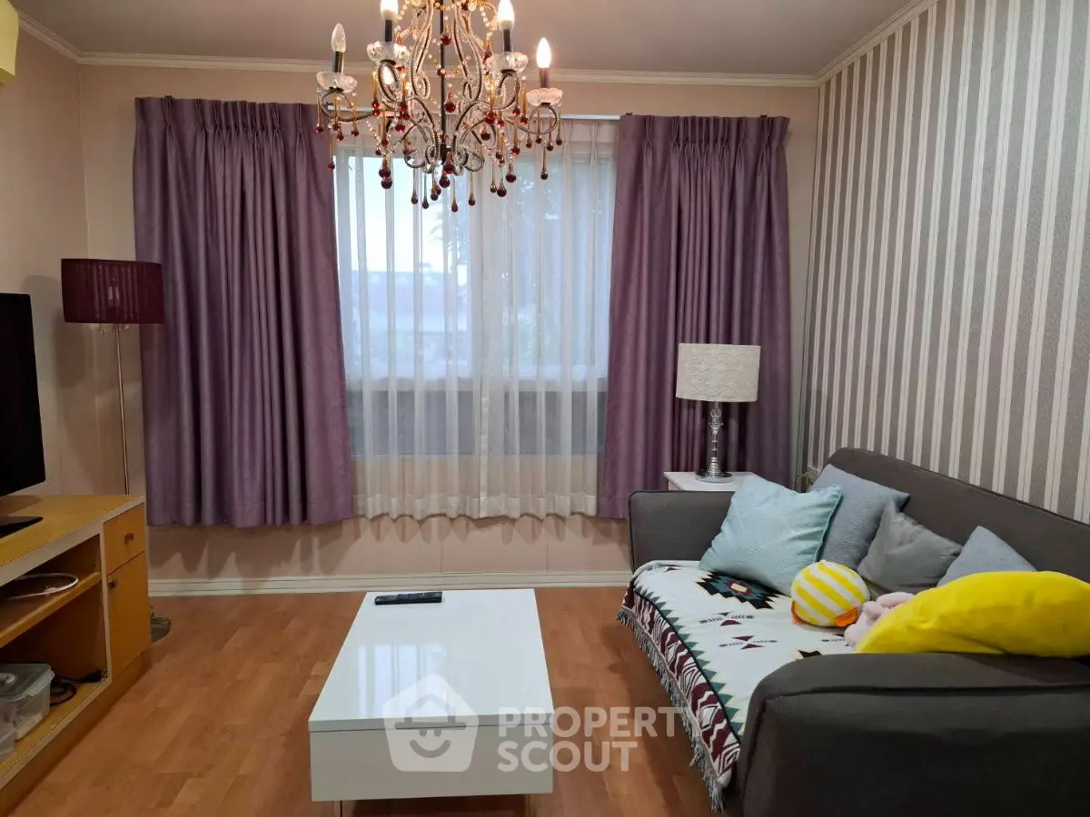 Charming living room with elegant chandelier and cozy sofa, perfect for relaxation.