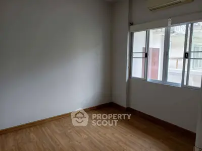 Spacious empty room with wooden flooring and large window, perfect for customization.