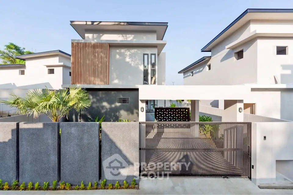 Modern minimalist house exterior with sleek design and gated entrance, showcasing contemporary architecture.