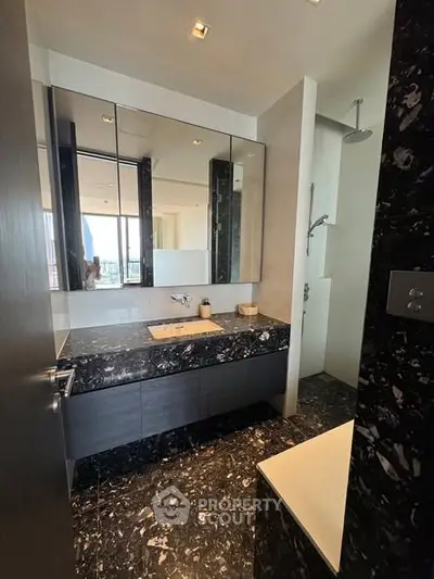 Luxurious modern bathroom with sleek black marble finishes and elegant fixtures.
