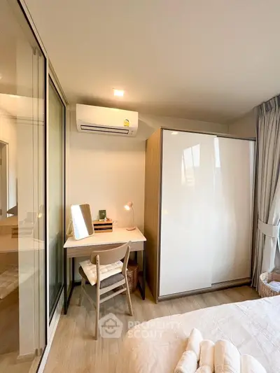 Cozy bedroom with modern furniture and natural light, featuring a stylish wardrobe and a compact study area.