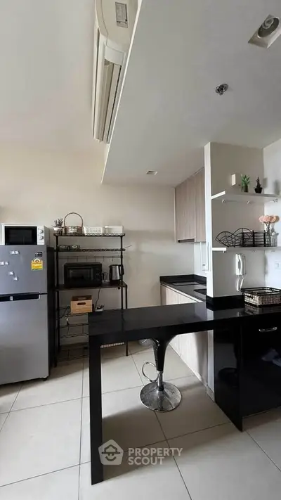 Modern kitchen with sleek black countertops and stainless steel appliances in a stylish apartment.