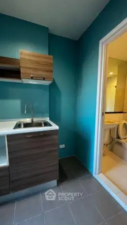 Modern compact kitchen with wooden cabinets and adjacent bathroom in a stylish apartment.