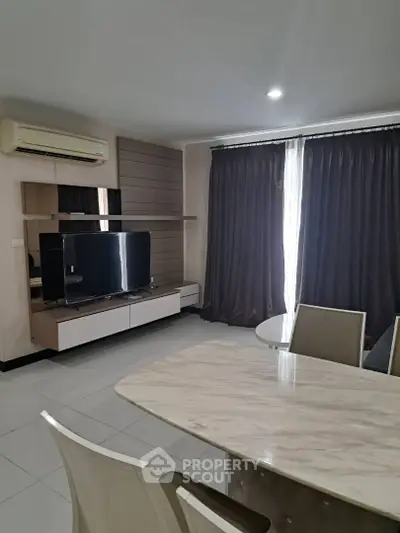 Modern living room with sleek furniture and large TV, featuring elegant curtains and air conditioning.