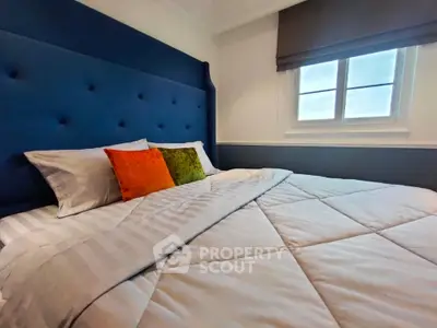Cozy bedroom with plush blue headboard and colorful pillows