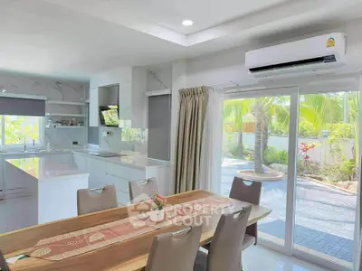 Modern kitchen and dining area with garden view, featuring sleek design and natural light.