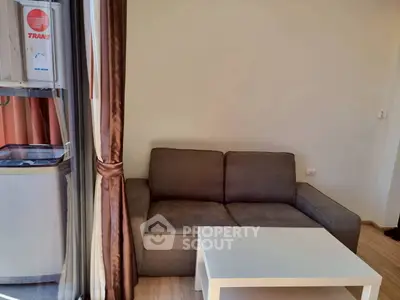 Cozy living room with modern sofa and sleek white coffee table near large window.