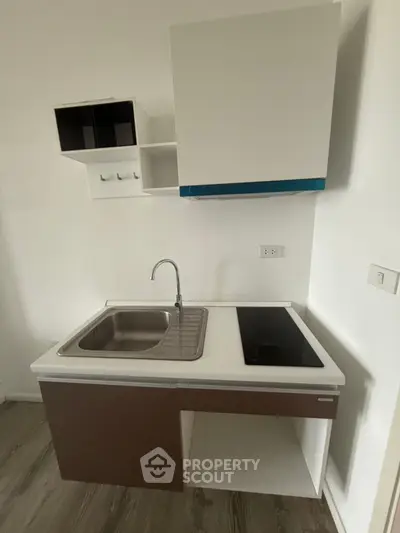 Modern compact kitchen with sleek cabinetry and built-in electric cooktop, perfect for urban living.
