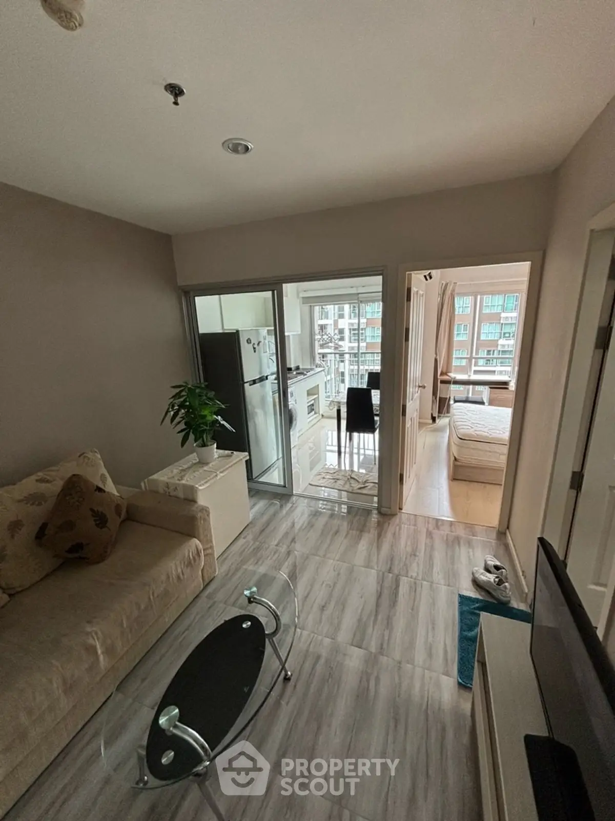 Modern apartment interior with open living room and kitchen, featuring sleek furniture and natural light.